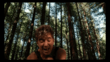 a man with curly hair is standing in the woods with his eyes closed
