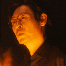 a man wearing glasses and a black shirt looks up