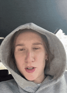 a person wearing a grey hoodie with a hood