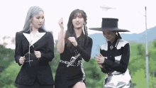 three women are standing next to each other and one is wearing a black hat
