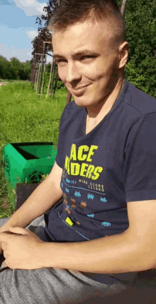 a man wearing an ace riders t-shirt sits on a bench