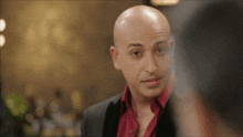 a bald man with a red shirt and a black jacket