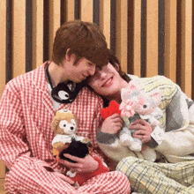a man and a woman are holding stuffed animals and one of the stuffed animals has a heart on it
