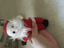a person is holding a stuffed santa claus toy in their hand
