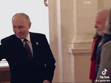 a man in a suit and tie is standing next to another man in a red coat
