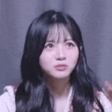 a close up of a woman 's face with long black hair making a funny face .