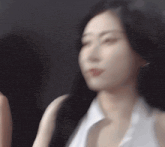 a woman with long black hair and a white shirt is looking at the camera .