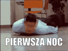 a man in a blue shirt is laying on the floor with the words pierwsza noc below him