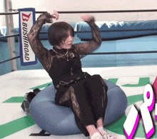 a woman sitting on a blue bean bag in front of a bushiroad sign