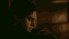 a close up of a man 's face in a dark room looking at something .