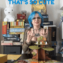 a woman with blue hair stands in front of a stack of board games including catan and wingspan