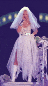 a woman in a bride 's veil is singing into a microphone
