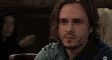 a man with long hair and a beard is sitting at a table with a woman .