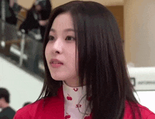 a woman wearing a red jacket and a white sweater with cherries on it .