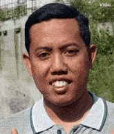 a man wearing a grey shirt is smiling with the word vidu visible in the corner