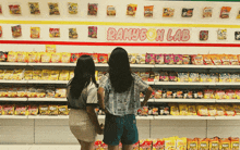 two women are standing in front of a wall that says banyson lab on it