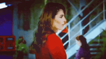 a woman in a red jacket is standing in front of stairs .