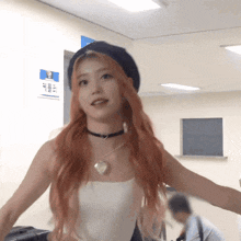 a woman with red hair is wearing a black hat and a white tank top