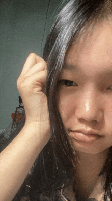 a close up of a woman 's face with a hand on her head