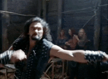 a man is fighting another man in a room with a group of people watching .