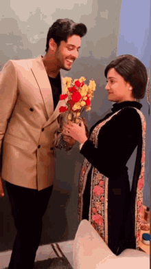 a man is giving flowers to a woman who is holding a vase of flowers