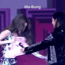 a woman in a floral dress is being held by another woman in a black jacket with ma- bung written on the bottom