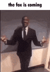 a man in a suit and tie is standing with his arms outstretched and the words the fox is coming above him .