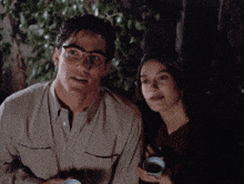 a man and a woman are sitting next to each other and the man is wearing glasses