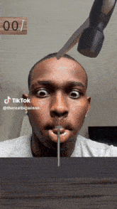 a man is holding a nail in his mouth with a hammer behind him