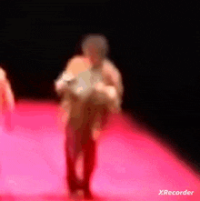 a blurred image of a person walking on a red carpet with xrecorder written on the bottom right