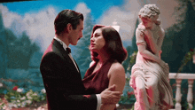 a man and a woman are hugging in front of a statue