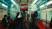 a woman with blue hair is dancing on a subway car with graffiti on the wall .