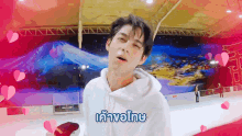 a man in a white hoodie is standing on a ice rink with hearts surrounding him