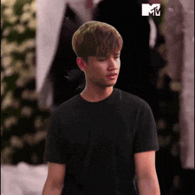 a man in a black t-shirt is standing in front of a mtv logo