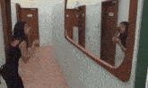 a woman is applying makeup in front of a mirror in a hallway