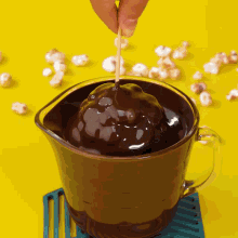 a person is dipping a popcorn ball in chocolate sauce