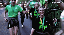 a group of people walking down a street with a sign that says wolfe tv in the background
