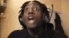 a man with dreadlocks is wearing headphones and making a funny face .