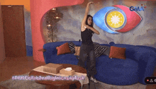 a woman is dancing in a living room with a gma logo in the background
