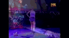 a woman in a purple skirt stands on a stage in front of a sign that says fox sports
