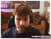 a man wearing headphones is talking into a microphone while sitting in front of a couch .