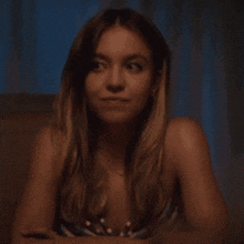 a woman in a striped top is sitting on a couch looking at the camera .