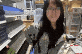 a woman wearing glasses is standing in front of a shelf that has a sticker that says ' abc ' on it