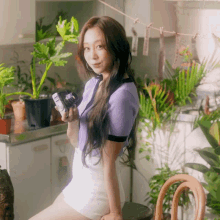 a woman in a purple top and white shorts holds a camera
