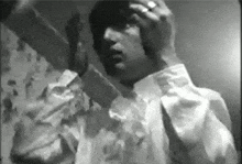 a black and white photo of a man holding his head .