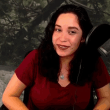a woman in a red shirt is sitting in front of a microphone and smiling