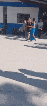 a group of people are walking on a concrete floor in front of a building .