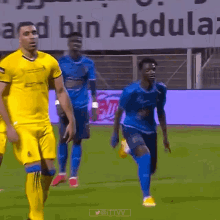 a group of soccer players are running on a field in front of a banner that says abdullah