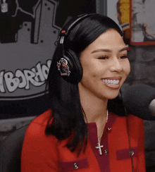a woman wearing headphones with a sticker that says ' boston ' on it smiles