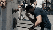a man in a blue shirt is washing his face in a fountain